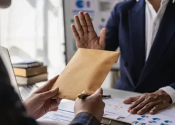 Businessperson rejecting a suspicious envelope, illustrating internal fraud risk mitigation. - Supply Chain News