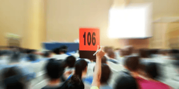A crowd of people holding up a sign at an auction.