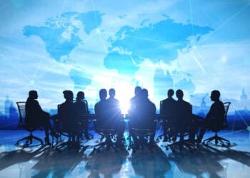 A group of business people sitting around a table in front of a world map at the G20 Summit in New Delhi.