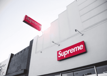 A Supreme store with a sign on the side of the building featuring an impressive Supreme T-Shirt Collection.