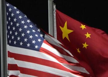 Two American and Chinese flags flying in front of each other at a Commerce Department event highlighting the countries' growing cooperation in China's AI industry.