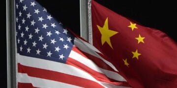 Two American and Chinese flags flying in front of each other at a Commerce Department event highlighting the countries' growing cooperation in China's AI industry.