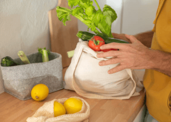 A man is exploring ethical sourcing by putting carefully selected vegetables into a tote bag.