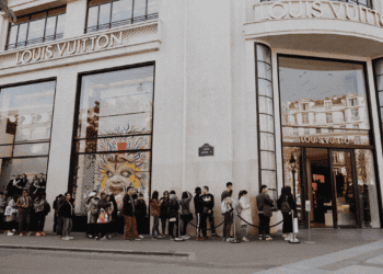 A line of people waiting outside of a luxury goods store.