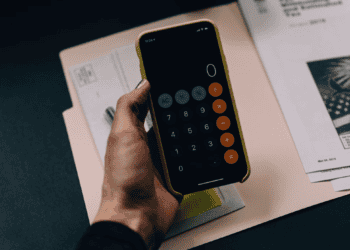 A person analyzing a proposed luxury goods tax using a calculator on their phone.