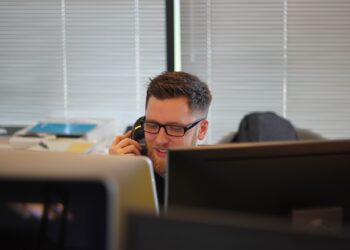 A man strengthening Congressional leadership while talking on a phone in front of a computer.