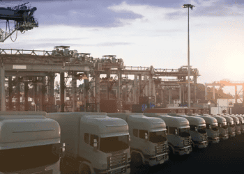 A group of sustainable trucks parked in front of a warehouse, contributing to last-mile electrification in the logistics sector.