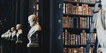 Busts of historical figures line a library wall filled with antique law books; AI regulation. - Supply Chain News