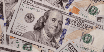 A pile of one hundred dollar bills representing investment opportunities on a white background.