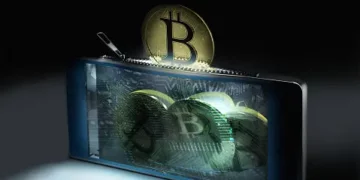 A phone with a bitcoin sitting on top of it, emphasizing its connection to the UK Investment Manager.