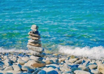 A stack of rocks on a beach near the ocean, showcasing G7 and potential consequences.