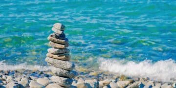 A stack of rocks on a beach near the ocean, showcasing G7 and potential consequences.