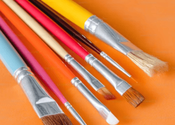 A collection of artistry paint brushes on an orange background.
