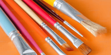 A collection of artistry paint brushes on an orange background.