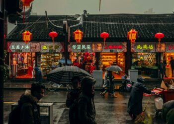 A group of people walking down a street in a rainy day in China.