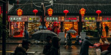 A group of people walking down a street in a rainy day in China.