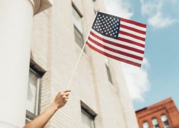 A woman waving an American flag in front of a building symbolizes the strong role America's allies play in export control measures.