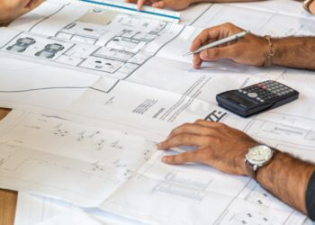 Team collaborating on blueprints, developing supply chain resilience plans. - Supply Chain News