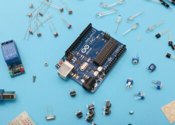 An Arduino board and other electronic components on a blue background, complying with export controls.
