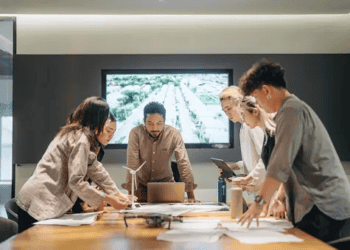 A group of people engaging in Corporate Social Responsibility initiatives, standing around a table in a conference room.