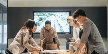 A group of people engaging in Corporate Social Responsibility initiatives, standing around a table in a conference room.