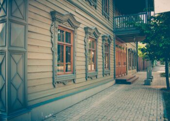 Revise the description of a house: A wooden building with windows and a balcony.