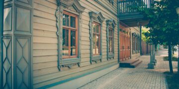Revise the description of a house: A wooden building with windows and a balcony.