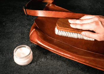 A person is gently brushing a luxury leather bag.