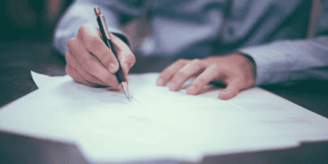 Person signing a document with a pen. Survey results. - Supply Chain News