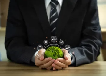 Businessperson holding a small, green globe representing environmental responsibility and corporate sustainability. - Supply Chain News