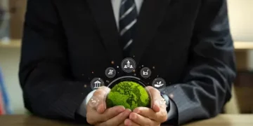 Businessperson holding a small, green globe representing environmental responsibility and corporate sustainability. - Supply Chain News