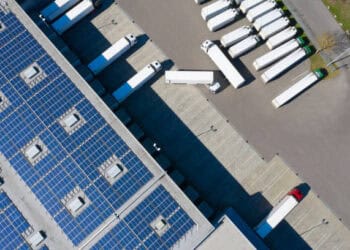 An aerial view of trucks parked in a parking lot with solar panels, showcasing sustainable supply chain practices in Latin America.