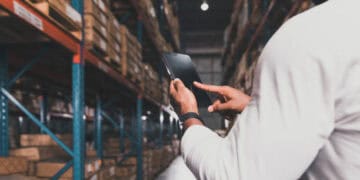 Warehouse worker using tablet to manage inventory. Streamlining logistics for SMEs. - Supply Chain News