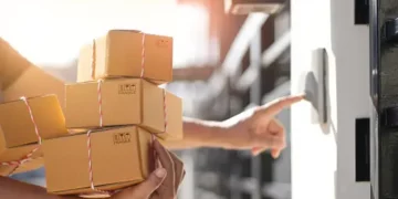 Delivery person ringing doorbell, holding stack of eco-friendly cardboard boxes. Greener deliveries. - Supply Chain News