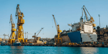 Large cargo ship in dry dock with multiple cranes. Green logistics in action. - Supply Chain News