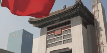 A Chinese flag flying in front of a building in China.