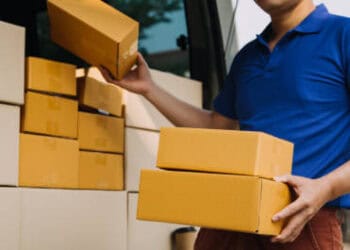 Delivery driver loading cardboard boxes into a truck. Seamless delivery 'one-stop shop' concept. - Supply Chain News