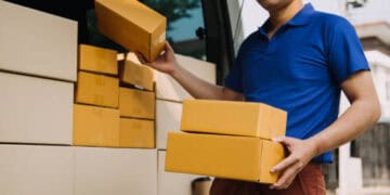 Delivery driver loading cardboard boxes into a truck. Seamless delivery 'one-stop shop' concept. - Supply Chain News