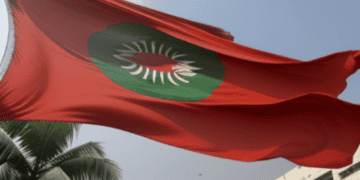 The flag of Bangladesh flies in front of a building amidst political turmoil.