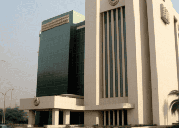 Former Central Bank Governor Emefiele oversees Nigeria's levies inside a large white building with a car in front of it.