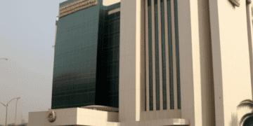 Former Central Bank Governor Emefiele oversees Nigeria's levies inside a large white building with a car in front of it.