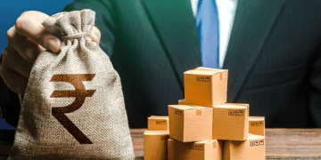 Businessperson holding a money bag with the Indian Rupee symbol, alongside a stack of cardboard boxes. - Supply Chain News
