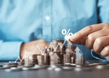 Hands arranging stacks of coins with upward trending graph and percentage symbol; illustrating financial growth. - Supply Chain News