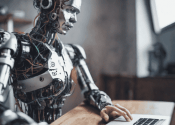 A robot addressing the AI skills gap with a laptop at a desk.