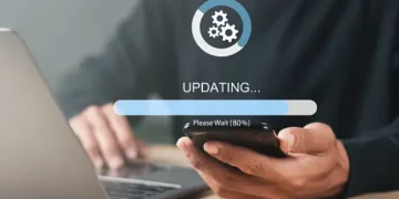 Person using laptop and phone, 80% update progress bar shown. Cybersecurity update in progress. - Supply Chain News