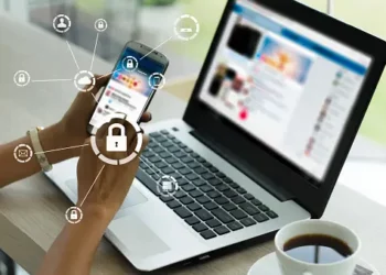 Person using laptop and phone, cybersecurity icons displayed. Homeland Security awareness. - Supply Chain News