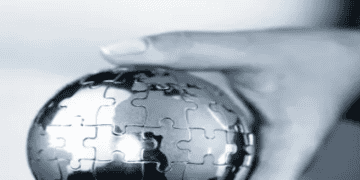 Hand holding a metal puzzle globe representing global climate change challenges and solutions for COP28. - Supply Chain News