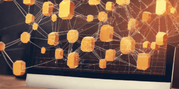 Computer screen displays a network of interconnected orange cubes, illustrating distributed ledger technology. - Supply Chain News