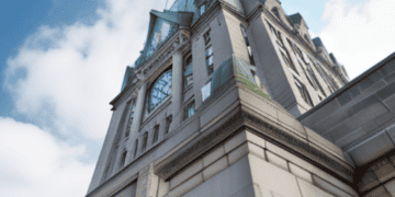 The Royal Bank of Canada, a building with a clock on top of it, faces job cuts amidst economic downturn.