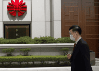 A man wearing a face mask walks past a building in China.